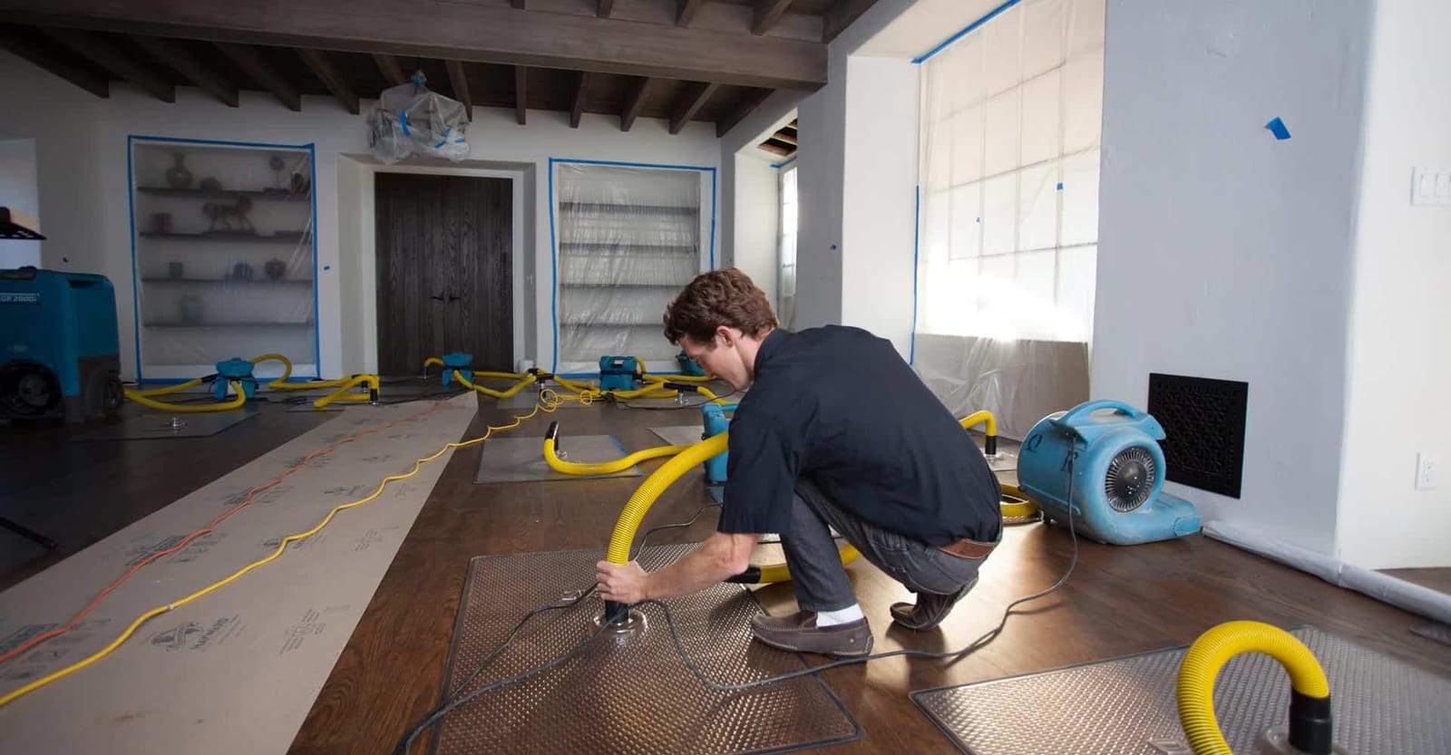 Technician setting up under-floor drying system with air movers