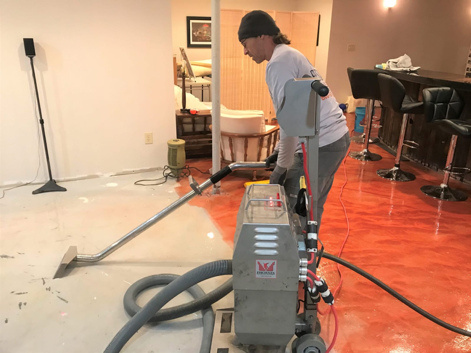 Water extraction technician using industrial extractor on flooded floor